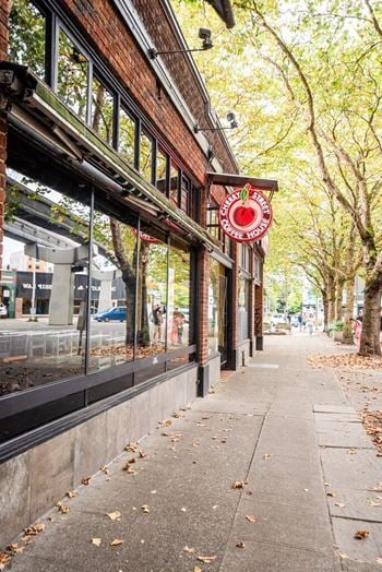 A red sign with a white apple on it is on the side of a building.