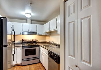 An empty kitchen with white cabinets and stainless steel appliances