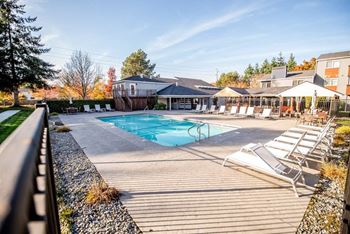 A pool area with sun loungers and a building in the background.