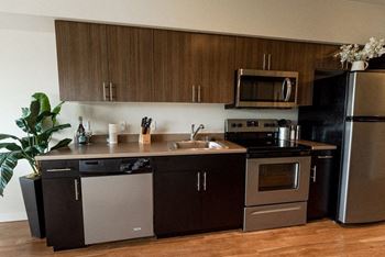 A modern kitchen with dark brown cabinets and stainless steel appliances.