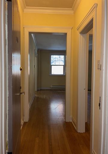 Seattle apartment for rent - A long hallway with a door on the left and a window on the right.