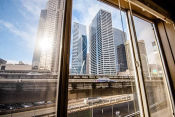 A cityscape is seen through a window with a clear blue sky.