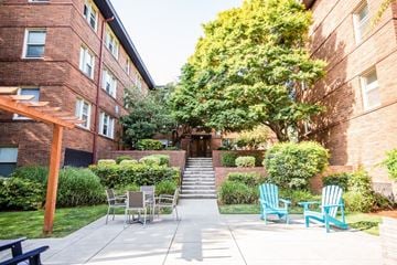 Seattle apartment for rent - the backyard of a building with blue chairs and a tree