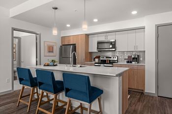 A kitchen with a large island with three blue chairs
