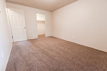 An empty bedroom with carpeting and a white door
