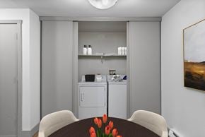 Tacoma apartment for rent - A kitchen with a dining table and chairs with a vase of red flowers on the table.