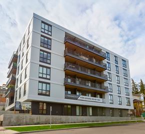 Calgary apartment for rent - A modern apartment building with balconies and a sign that reads "Lynbrook Now Leasing".