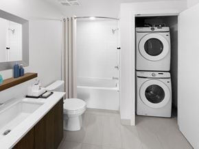 Calgary apartment for rent - A white bathroom with a toilet, sink, and a washing machine in the doorway.