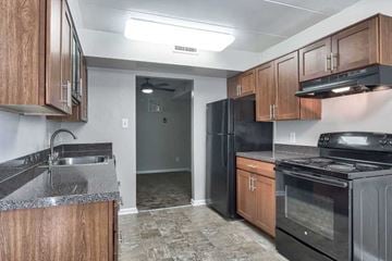 Laurel apartment for rent - an empty kitchen with black appliances and wooden cabinets