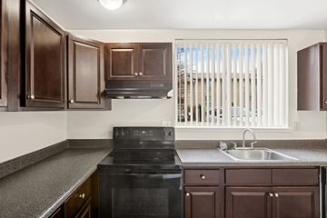 Gaithersburg apartment for rent - A kitchen with dark brown cabinets and a black stove top oven.