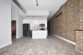 Chicago apartment for rent - A kitchen with a white island and a brick wall.