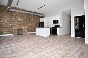 Chicago apartment for rent - A room with a brick wall and wooden flooring.