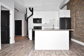 Chicago apartment for rent - A kitchen with white cabinets and a black fridge.