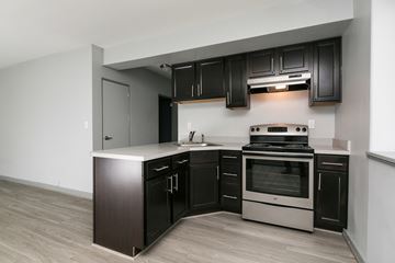 Greenbelt apartment for rent - A modern kitchen with dark wood cabinets and stainless steel appliances.