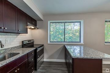 Greenbelt apartment for rent - A kitchen with dark wood cabinets and a granite countertop.