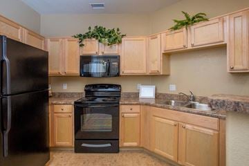 Glendale townhouse for rent - A kitchen with wooden cabinets and a black refrigerator.