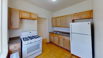 Chicago apartment for rent - A kitchen with a white fridge, stove and wooden cabinets.