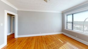 Chicago apartment for rent - A room with wooden floors and a window overlooking a parking lot.
