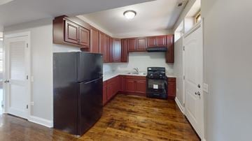 Chicago apartment for rent - A kitchen with a black refrigerator and wooden floors.