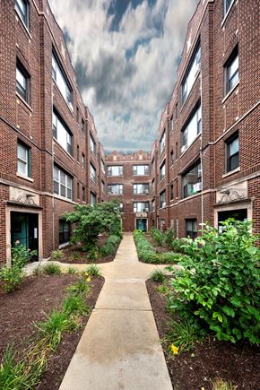 Chicago apartment for rent - the walkway between two brick apartment buildings with a cloudy sky in the background
