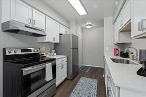 Newport apartment for rent - A modern kitchen with a black stove top oven and white cabinets.
