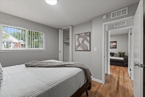 Ypsilanti apartment for rent - A bedroom with a large bed and a view of the backyard through the window.