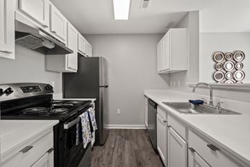 Monroe apartment for rent - A kitchen with a black stove top oven and white cabinets.