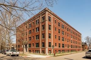 Detroit apartment for rent - A red brick building with green trim and a parking lot in front.