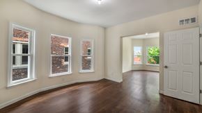 Detroit triplex for rent - A room with a white door and three windows with brick walls.