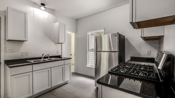 Detroit triplex for rent - A modern kitchen with white cabinets and stainless steel appliances.
