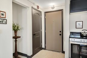 Detroit apartment for rent - A kitchen with a stove and oven, a plant on a stand, and two doors.