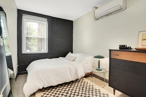 Detroit apartment for rent - A bedroom with a white bed and a black and white checkered rug.