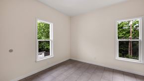 Detroit triplex for rent - A room with two windows showing a view of trees and a building.