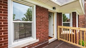 Detroit triplex for rent - A white window on a brick house with a wooden railing.