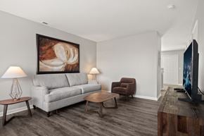 Monroe apartment for rent - A living room with a grey couch, a brown armchair, a wooden coffee table, and a painting on the wall.