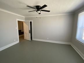 Detroit apartment for rent - an empty living room with a ceiling fan and a door to a bedroom