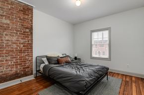 Detroit townhouse for rent - A bedroom with a brick wall and a bed.