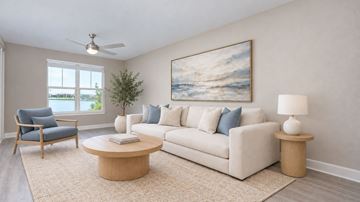 Orlando apartment for rent - A living room with a white couch, a blue chair, a round coffee table, and a painting on the wall.