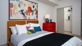 Portland apartment for rent - A bedroom with a large bed and a colorful painting above it.