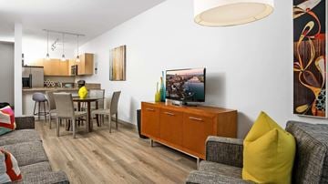 Portland apartment for rent - A living room with a grey couch, a yellow pillow, a wooden cabinet, and a painting on the wall.
