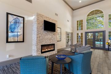 Dallas apartment for rent - A living room with a stone fireplace and a television above it.
