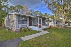 Tampa apartment for rent - A small house with a white and grey exterior is surrounded by greenery.