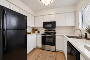 Tempe apartment for rent - A black fridge is in a kitchen with white cabinets.