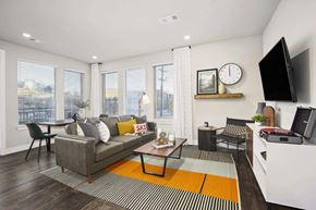 Golden apartment for rent - A living room with a grey couch, a coffee table, and a television.