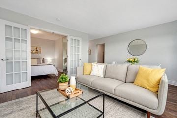 Nepean apartment for rent - A living room with a grey couch, a glass coffee table, and a mirror on the wall.