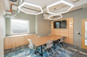 Seattle apartment for rent - A conference room with a long table and chairs, a television on the wall, and a window with a view of the sky.