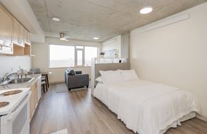 Seattle apartment for rent - A modern bedroom with a large bed and a kitchen area.