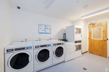 A washer and dryer room in a laundry room with washing machines and sinks