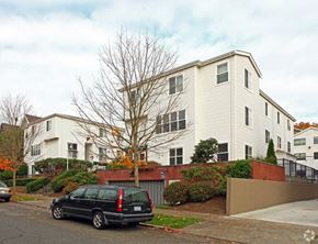 Seattle apartment for rent - a white apartment building with a black car parked in front