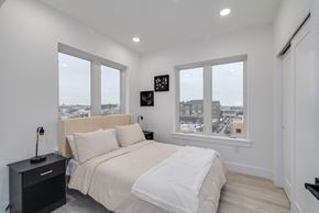 Philadelphia apartment for rent - A bedroom with a large bed and a city view through the windows.